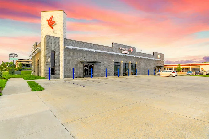 Modern commercial building with a large parking lot under a vibrant sunset sky