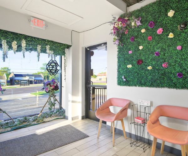 Bright and inviting waiting area with pink chairs, floral wall decor, and a glass door leading outside